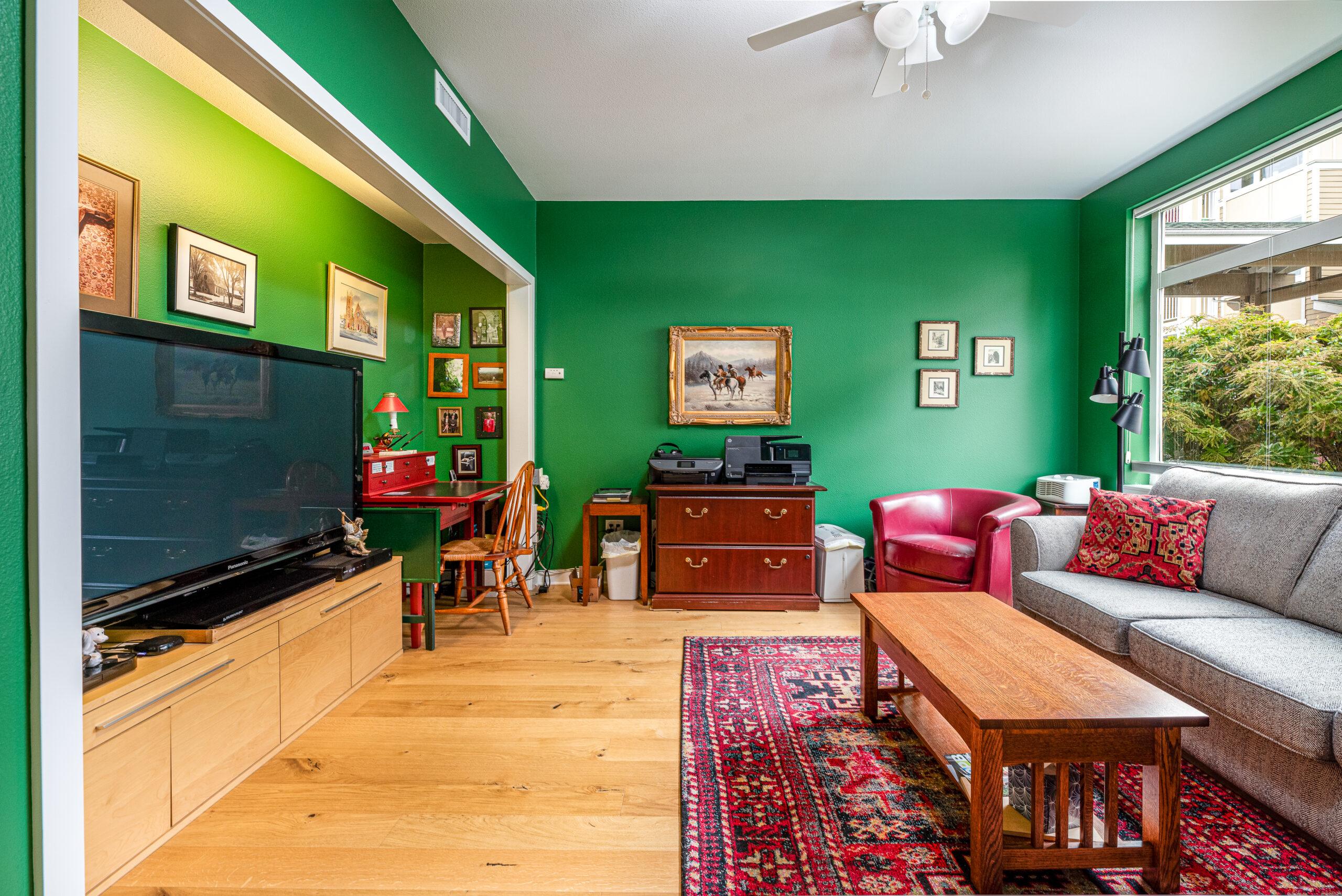 The living room of a residence at Cascade Manor. The walls are green, and there are several red accents throughout the room.