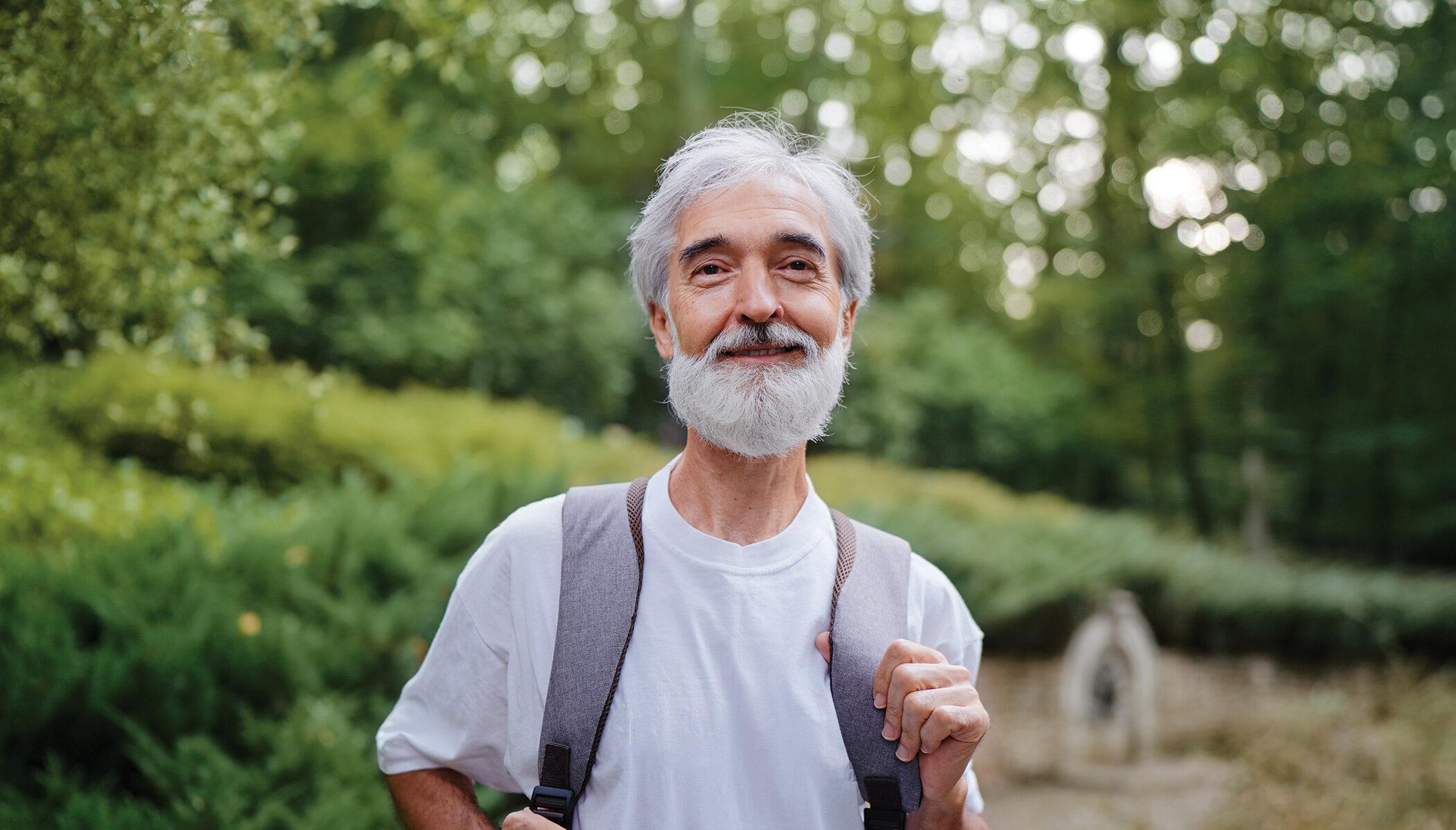 Outdoor portrait of an older man hiking outdoors and looking at the camera.